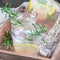 Homemade lemonade with lavender, fresh lemons and rosemary on a wooden tray, square format