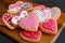 Homemade lovely patterned heart shaped royal icing cookies on  wooden breadboard