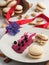 Homemade macarons with currant filling on a gray plate. Selective focus on cookies. Almonds, berries of blackcurrant and filling