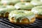 Homemade matcha green tea doughnuts covered with green matcha powder graze and grated pistachio on a cooling rack, close up.