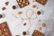 Homemade milk chocolate bars and pralines with dried berries and nuts on light background. Top view. Chocolatier work