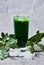 homemade Mint chlorophyll drink or juice or syrup in glass with water drops with ruscus plants and ice cubes .