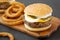 Homemade Mississippi Slug Burgers with onion rings on a rustic wooden board on a black background, side view. Close-up
