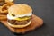 Homemade Mississippi Slug Burgers with onion rings on a rustic wooden board on a black background, side view. Copy space