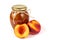 Homemade nectarine jam in a glass jar and fresh peaches on the wallpaper