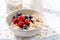 Homemade oatmeal with berries on white wooden board, closeup