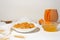 Homemade oatmeal porridge with seasonal autumn pumpkin in a white plate on a light background. autumn composition with wheat ears