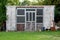 Homemade old concrete garden shed with discarded backyard junk in front and high trees in background