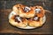 Homemade open pies with berry filling in a plate on a wooden textured surface.