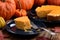 Homemade open pumpkin pie being eaten with orange pumpkins on dark plate rustic style