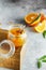 Homemade orange jam in glass jar on the wooden box on the gray background. Orange jam in swing-top jar on wood with orange slices