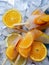 Homemade orange and peach popsicles with ice and citrus slices on light background