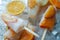 Homemade orange and peach popsicles with ice and citrus slices on light background