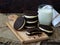 Homemade Oreo chocolate cookies with white marshmallow cream and glass of milk on dark background.