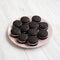 Homemade Oreos on a pink plate on a white wooden background, side view