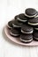 Homemade Oreos on a pink plate on a white wooden surface, side view