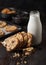 Homemade organic oatmeal cookies with raisins and apricots with baking tray and bottle of milk on grey wooden background. Black
