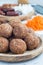 Homemade paleo energy balls with carrot, nuts, dates and coconut flakes, on wooden plate, vertical