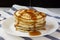 Homemade pancakes with butter and maple syrup on a white plate, side view. Close-up