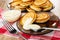 Homemade pancakes in oval dish, bowl with condensed milk, pancakes poured milk, spoon in saucer, fork on napkin on wooden table