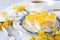 Homemade panna cotta and yellow fruits cubes sweets in coconut flakes and cup of tea, blooming forsythia decor