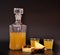 Homemade pineapple liqueur in a glass decanter and two glasses on a black background