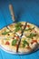 Homemade pizza with cheese and fresh arugula served over blue rustic wooden background.
