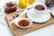 Homemade quince jam in a porcelain bowl with a cup of tea on a wooden tray.