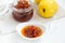 Homemade quince jam in a porcelain bowl with a cup of tea on a wooden tray.