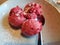 Homemade raspberry ice cream on frozen plate with fine sugar on top