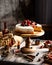 Homemade raspberry sliced biscuit cake with white cream and berries on top on wooden cake stand