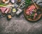 Homemade raw mincemeat on wooden plate with aged hand meat grinder, herbs spices and other ingredients on stone kitchen table