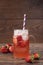 Homemade refreshing strawberry lemonade in a mason jar, fresh strawberries, wood background