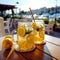 Homemade refreshing summer lemonade drink with lemon slices and ice in mason jars, in open air caffe on sea coast.