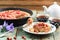 Homemade rhubarb pie in cast iron skillet with fresh wild strawberries on shabby turquoise boards with tea and bellflower