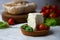 Homemade ricotta cheese with cherry-tomatoes and basil leaves in cork saucer