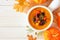 Homemade roasted autumn vegetable soup in an onion soup bowl, corner border on a white wood background with copy space