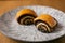 Homemade roll with poppy seeds on a plate on wooden background