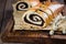 Homemade roll with poppy seeds on wooden board on wooden table background