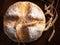Homemade round bread. Top view of a loaf of warm fresh peasant bread and wheat spikelets on a wooden background
