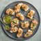 Homemade salmon crostini in black plate over grey background