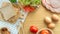 Homemade sandwich breakfast preparing. Whole wheat bread stacked on a wooden cutting board. Slice tomatoes and lettuce placed on a