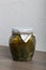 Homemade seasonal preparations. Pickled cucumbers in a glass jar. The neck of the can is wrapped in paper and tied with a rope