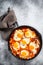 Homemade shakshuka, fried eggs, onion, bell pepper, tomatoes and parsley in a pan. Gray background. Top view