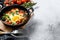 Homemade shakshuka, fried eggs, onion, bell pepper, tomatoes and parsley in a pan. Gray background. Top view. Copy space