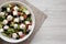 Homemade Shepards salad with cucumbers, feta and parsley in a white bowl on a white wooden table, top view. From above, overhead.