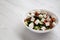 Homemade Shepards salad with cucumbers, parsley and feta in a white bowl on a white wooden surface, side view. Copy space