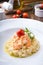 Homemade shrimp risotto served elegantly on a wooden table with cherry tomato and olives