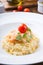 Homemade shrimp risotto served elegantly on a wooden table with cherry tomato and olives