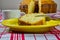 Homemade simple cake. Detail of homemade cake slice being cut with fork on a yellow plate with cup of coffee and cake in the backg